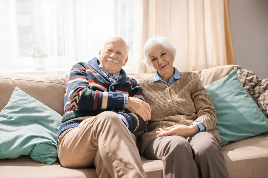 Older couple smiling at home on a sofa